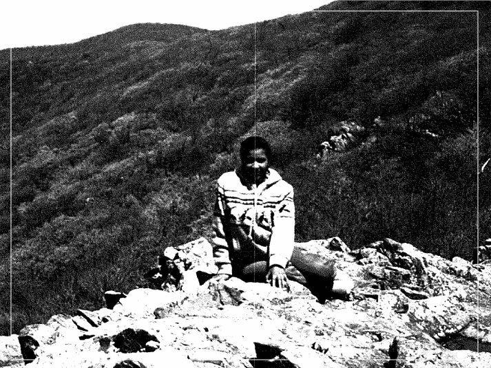 A person sitting on top of a rock.