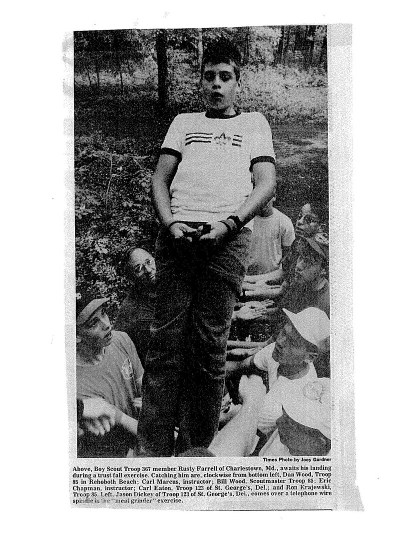 A man standing in the grass with people surrounding him.