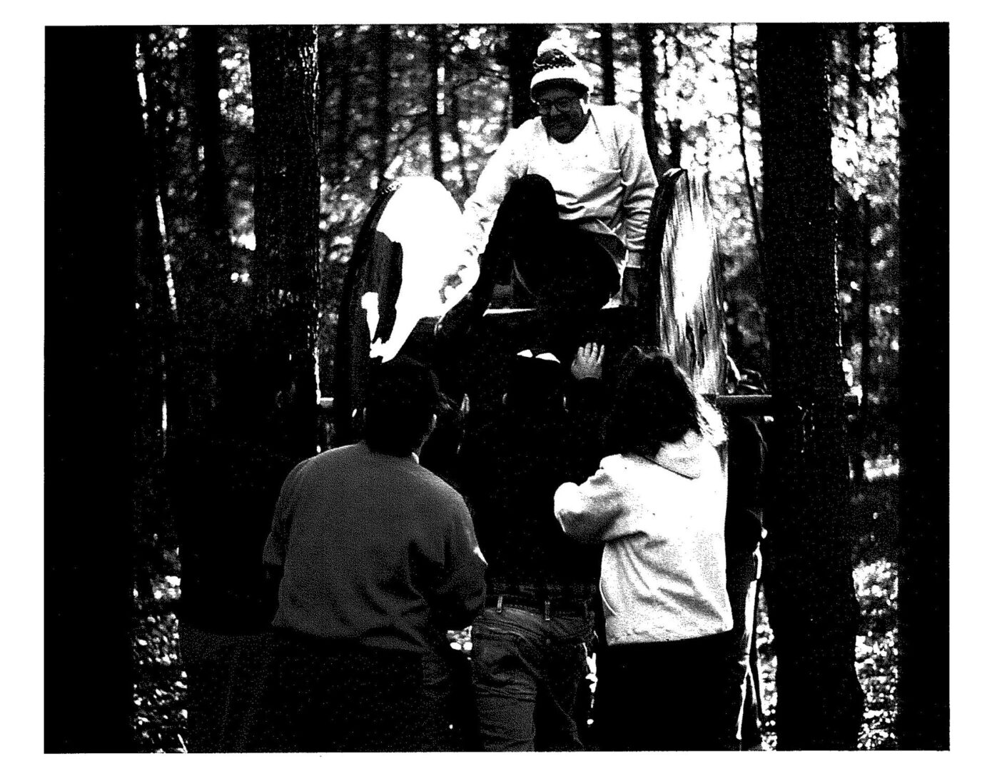 A group of people standing around in the woods.