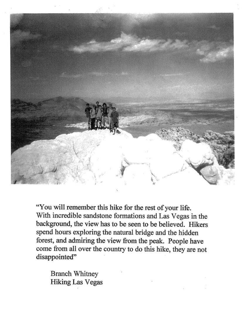 A black and white photo of two people standing on top of a hill.