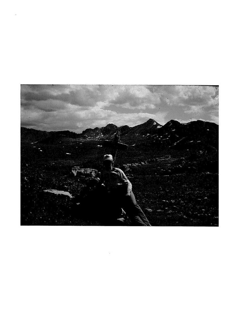 A black and white image of a man in the mountains.