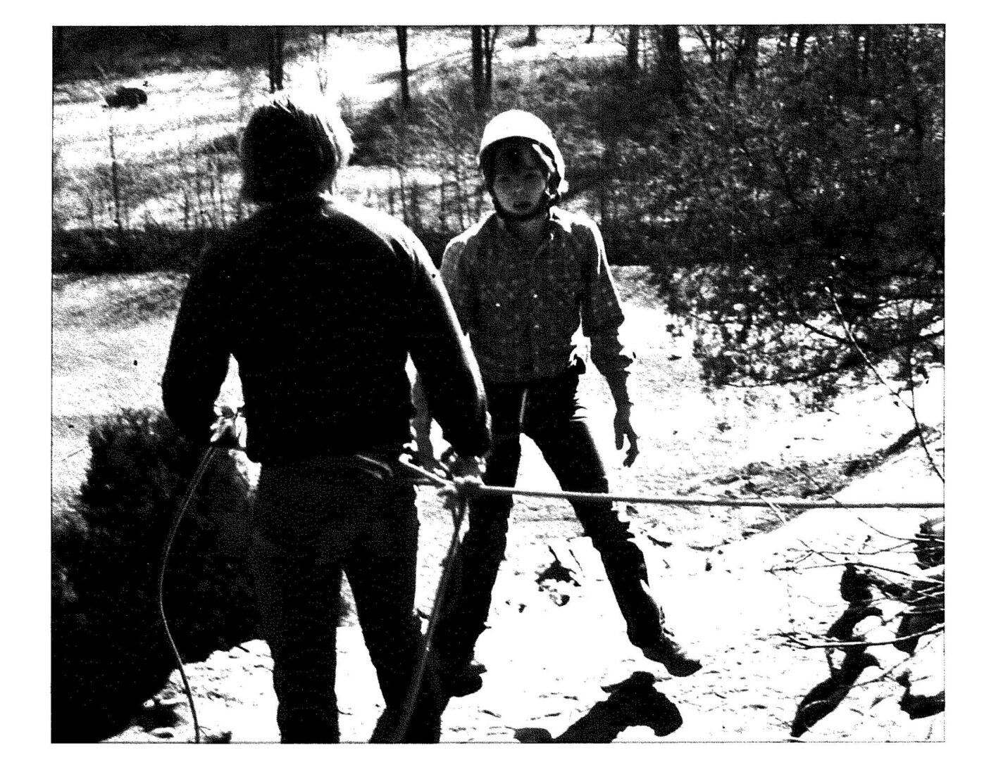Two people are standing in the snow with a rope.