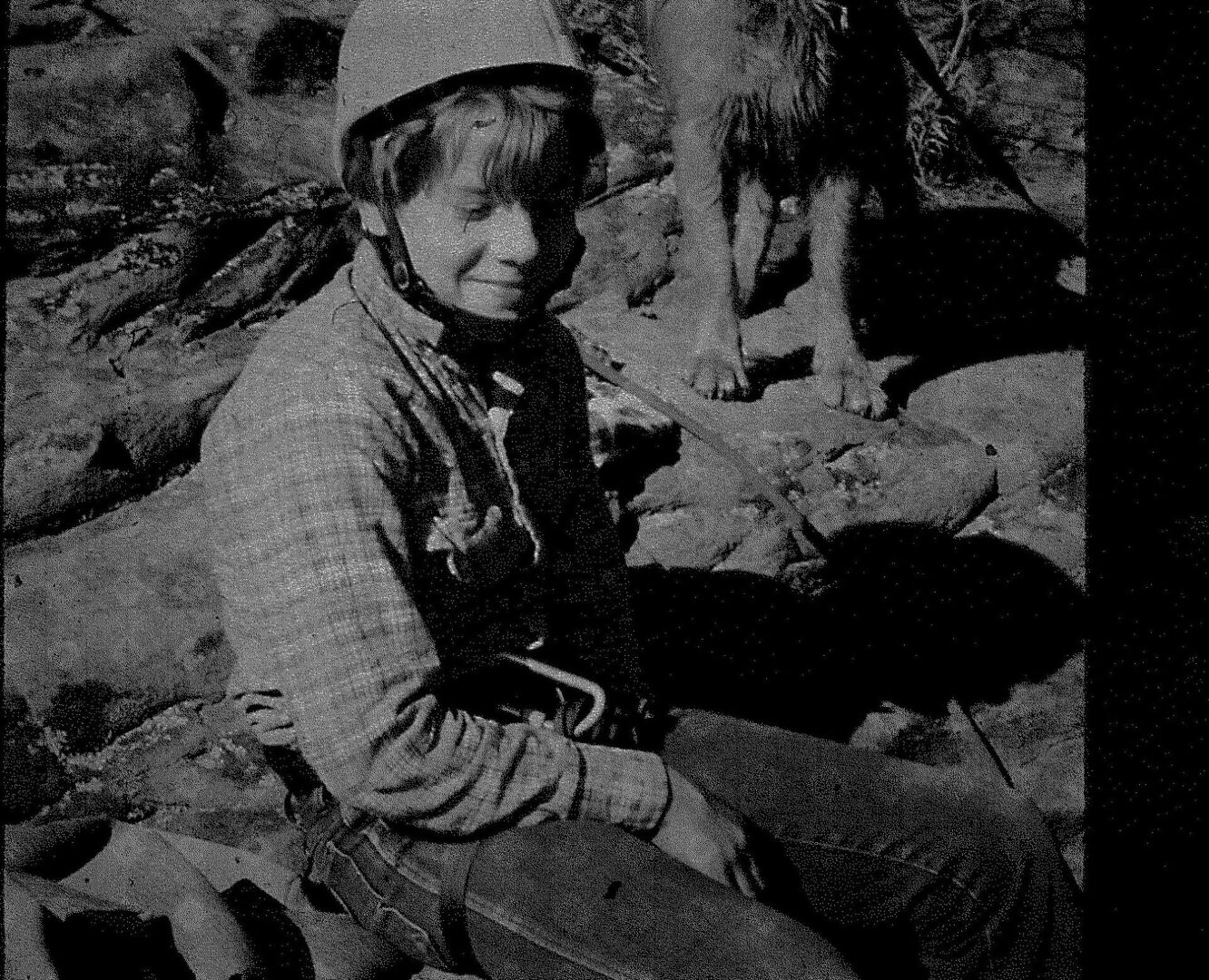 A man in camouflage sitting on top of rocks.