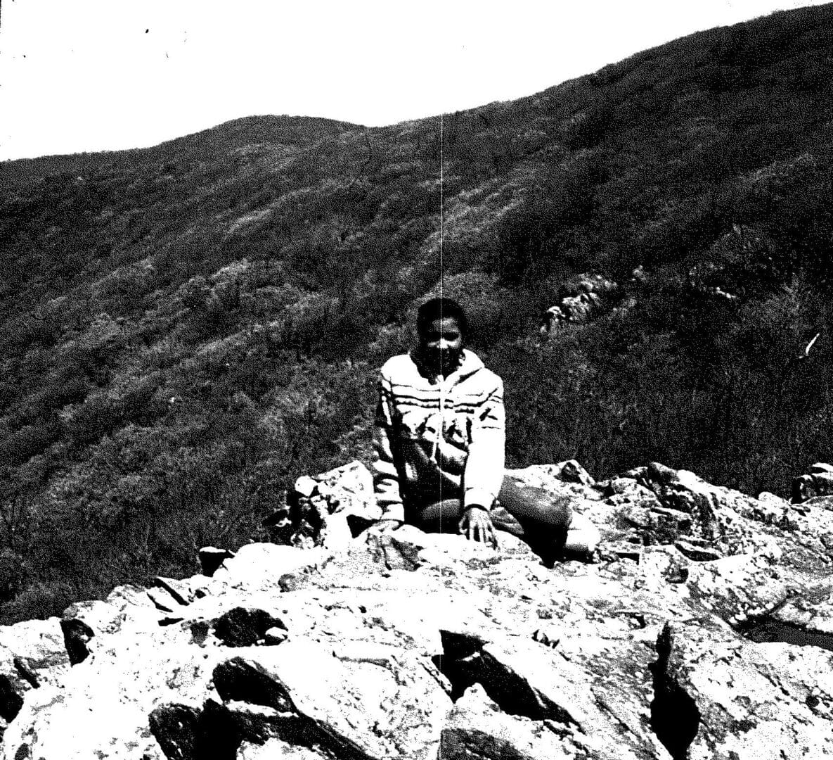 A person sitting on top of a rock.