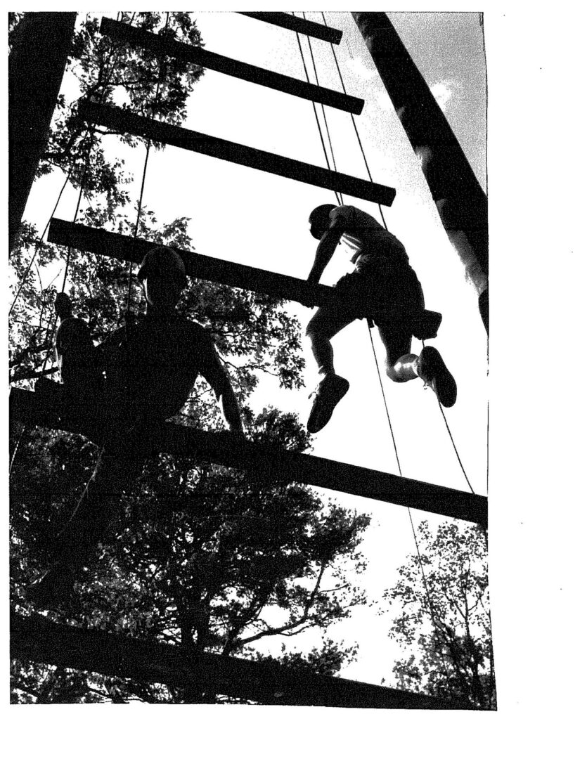 A man climbing up the side of an obstacle course.