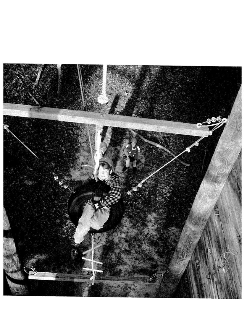 A black and white photo of a person hanging from a pole.