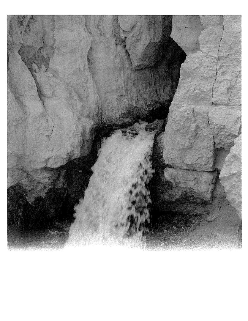 A black and white photo of rocks with a small hole in the middle.