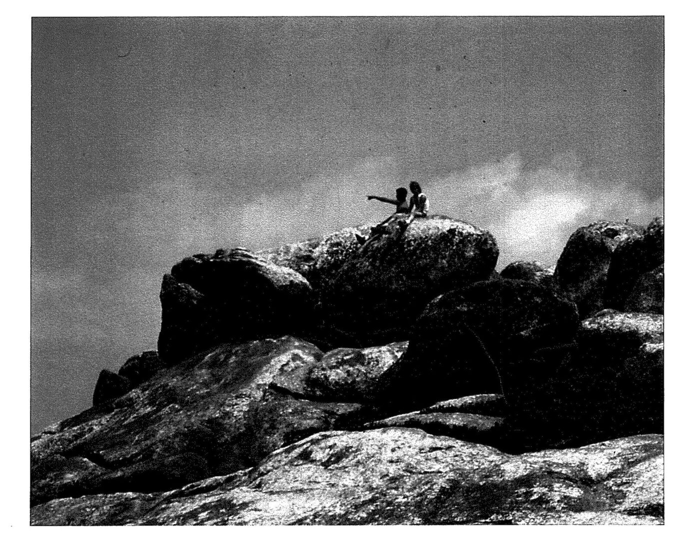 A black and white photo of two people on top of a mountain.