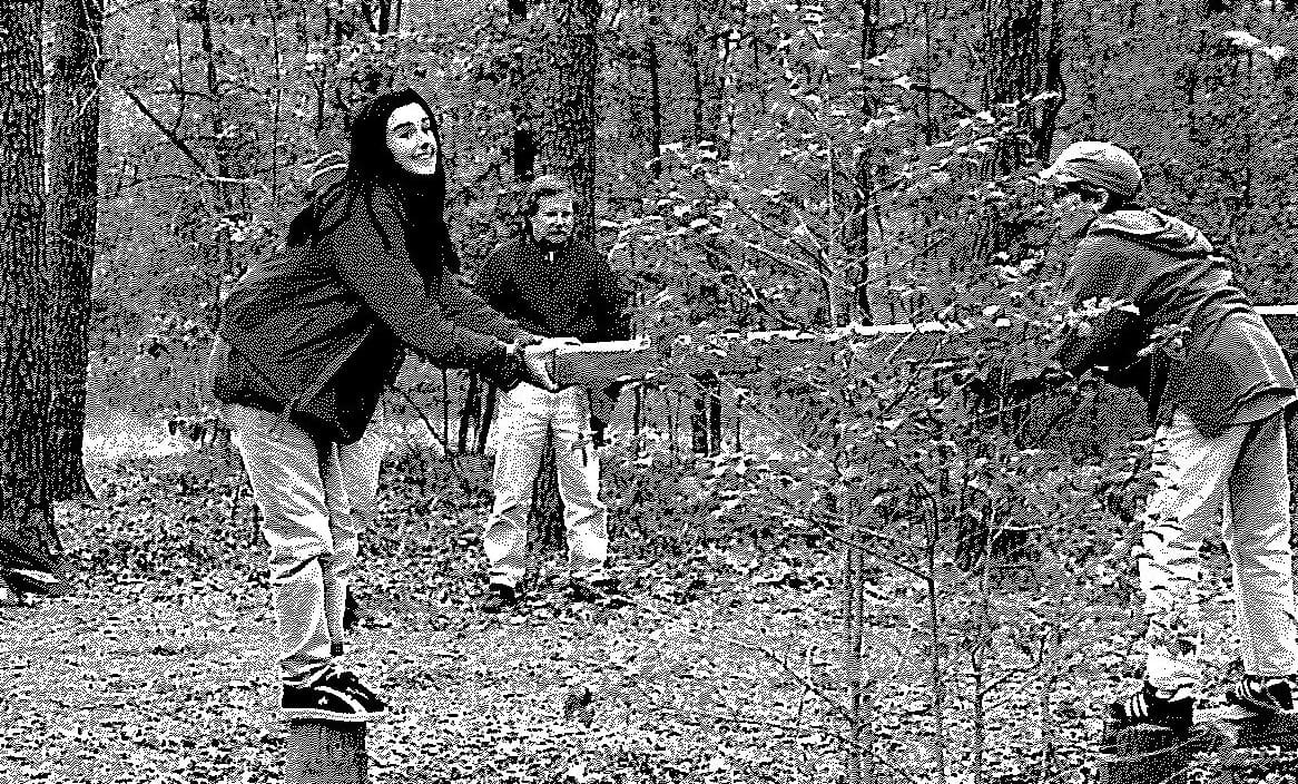 A man and woman in the woods playing frisbee.