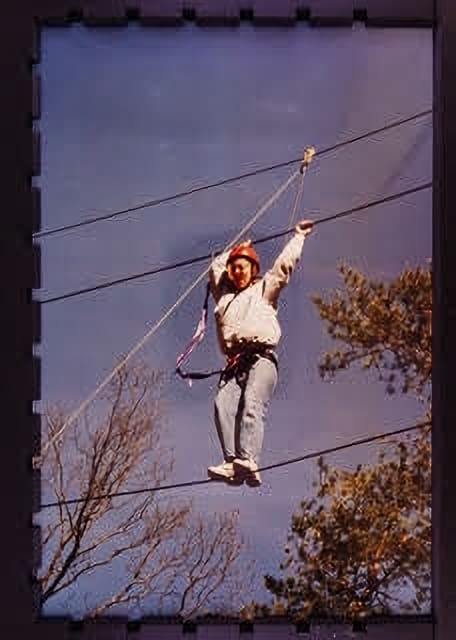 A man is hanging on to the ropes of a zip line.